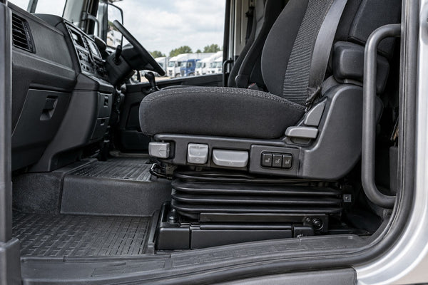 Original suspension seat and controls inside a parked lorry cab.